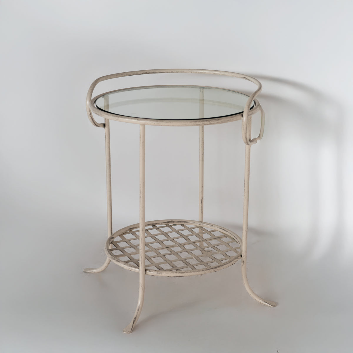 Bastogne bedside table seen from the side, with a scrolled edge around the glass top and curved legs
