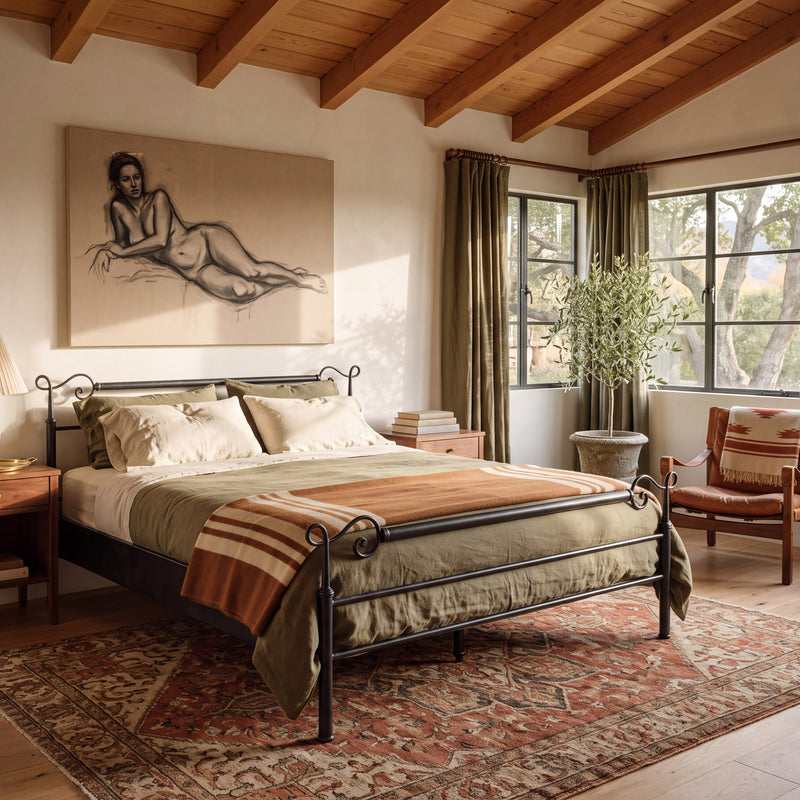 Cadiz smeedijzeren bed in zwart met krullen op de staanders, schuin vooraanzicht in een slaapkamer met houten balken