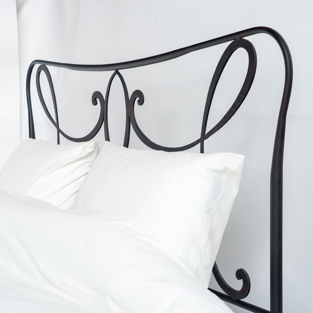 Detail des Kopfteils am Bett Houffalize mit gebogenem oberem Rand und Schnörkeln hinter weißen Kissen
