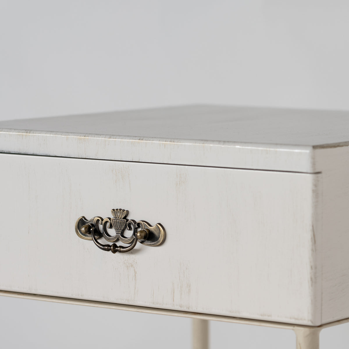 Detail of the drawer of the Damme bedside table with weathered white finish and antique brass handle