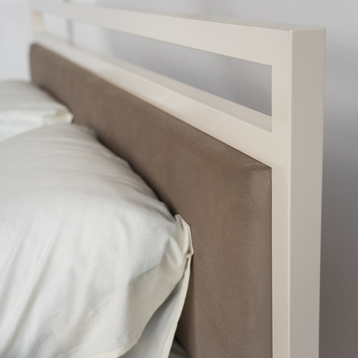 Detail des Kopfteils am Bett Driffield: cremeweißer oberer Rand mit offenem Feld über dem Paneel in Taupe