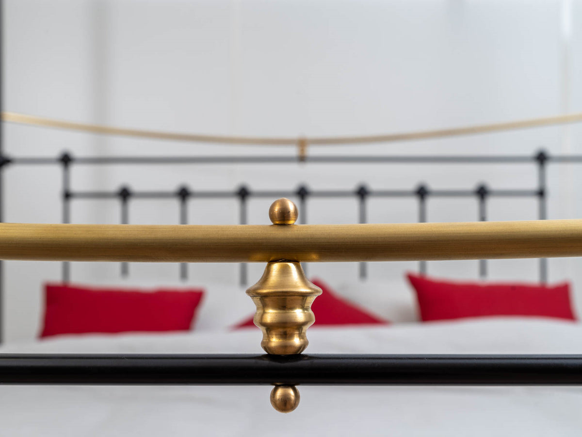 Close-up of the brass bar with decorative finial on the footboard of the Durham canopy bed showroom model 180x200cm