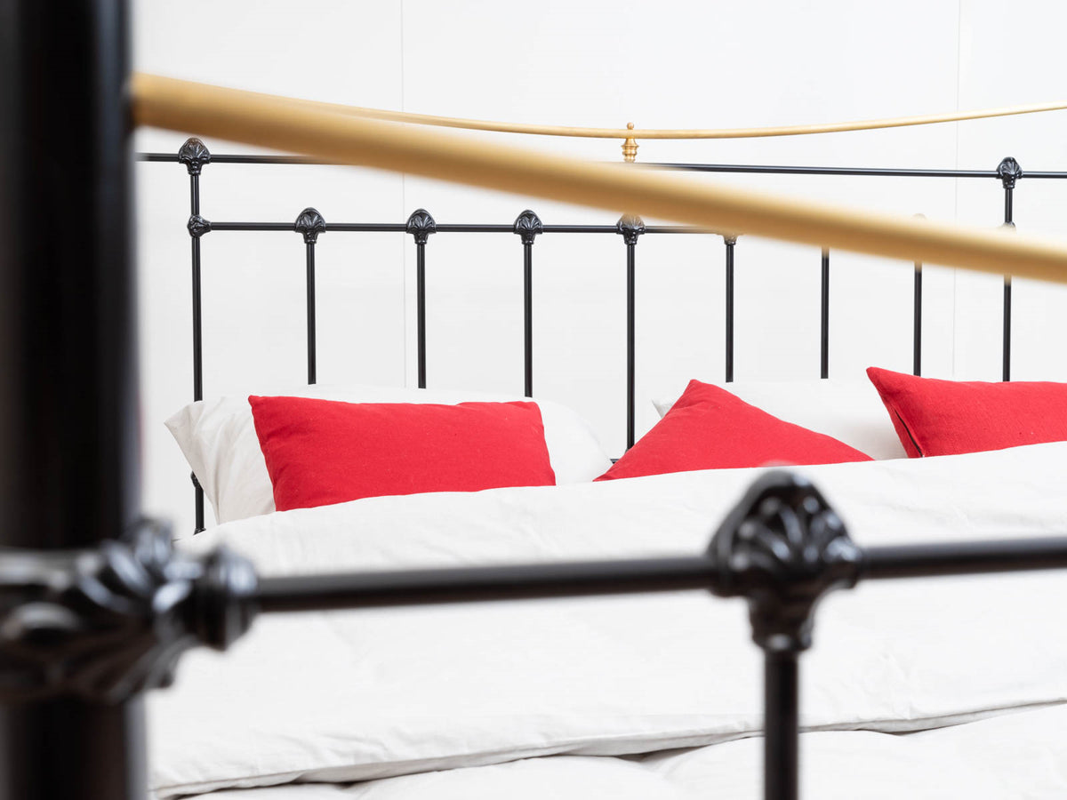 Black headboard with spindles and brass bar of the Durham canopy bed showroom model 180x200cm, with red cushions