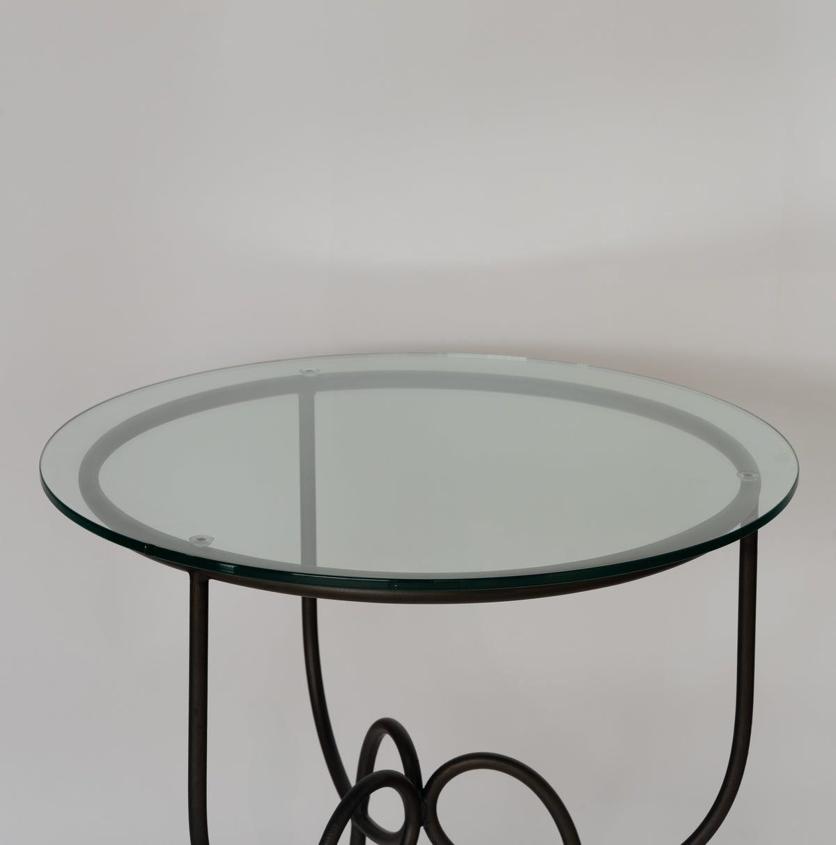 Detail of the round glass top on the black metal frame of the Entony bedside table