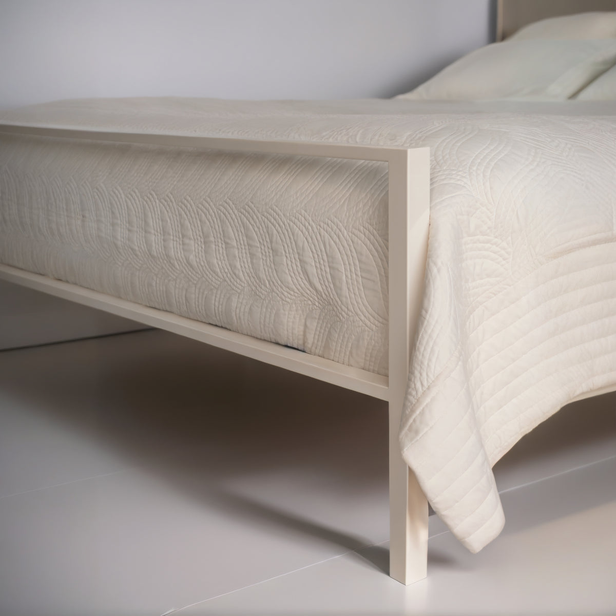 Detail des niedrigen cremeweißen Fußteils und des geraden Beins am Bett Ferndown mit weißer, gesteppter Tagesdecke