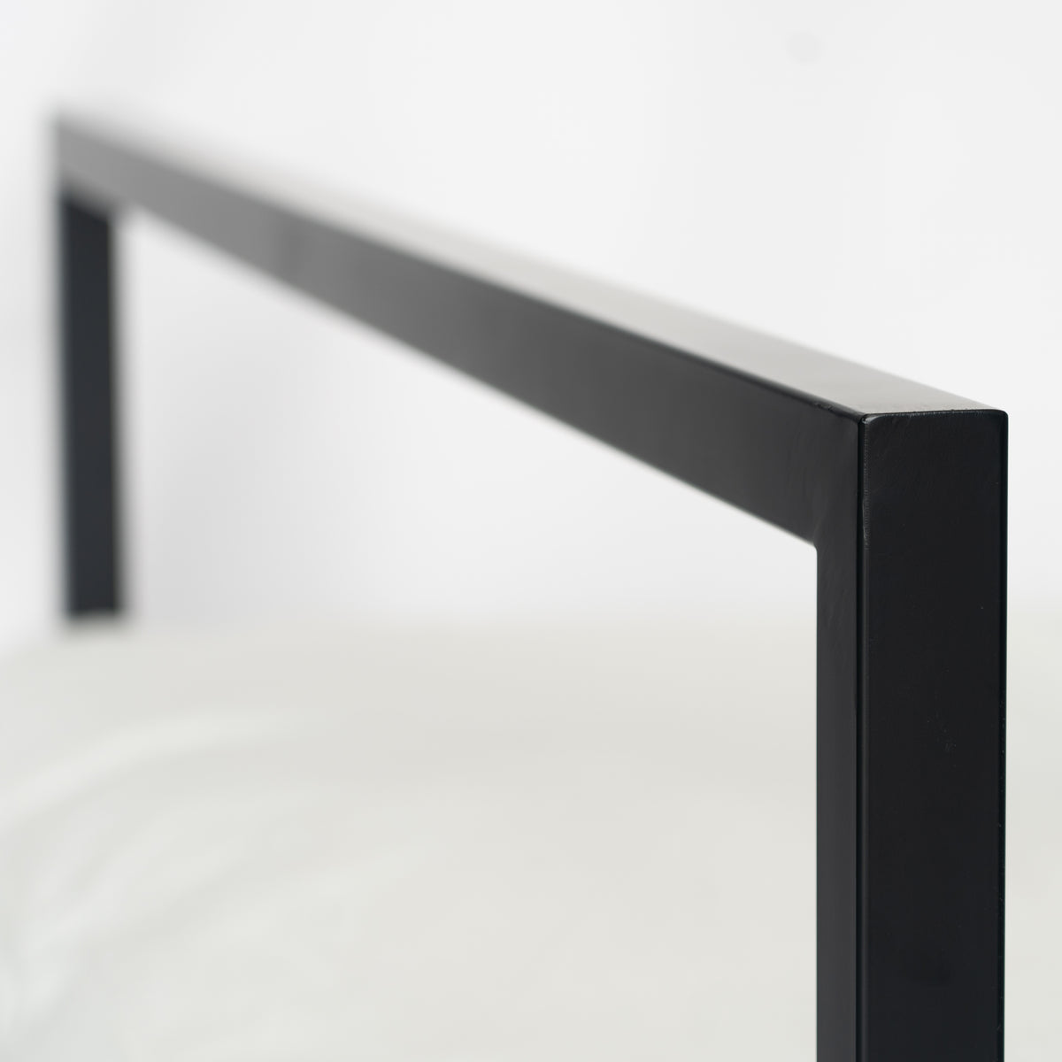 Nahaufnahme des geradlinigen schwarzen Metallrahmens am Bett Genk mit minimalistischer Formgebung