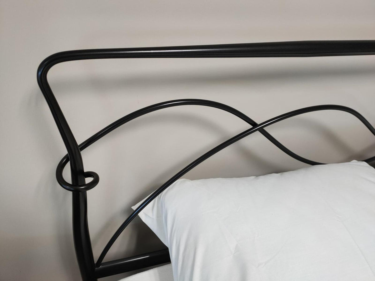 Detail of the headboard of the Girona showroom model 180×200 with black curved rails and a loop at the side