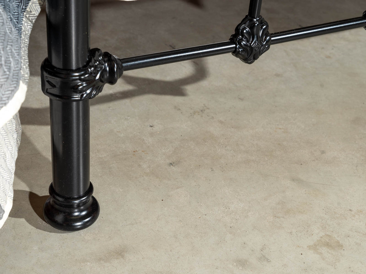 Detail des schwarzen Bettbeins mit Zierring und Ornament an der unteren Leiste des Betts Middleton auf Betonboden