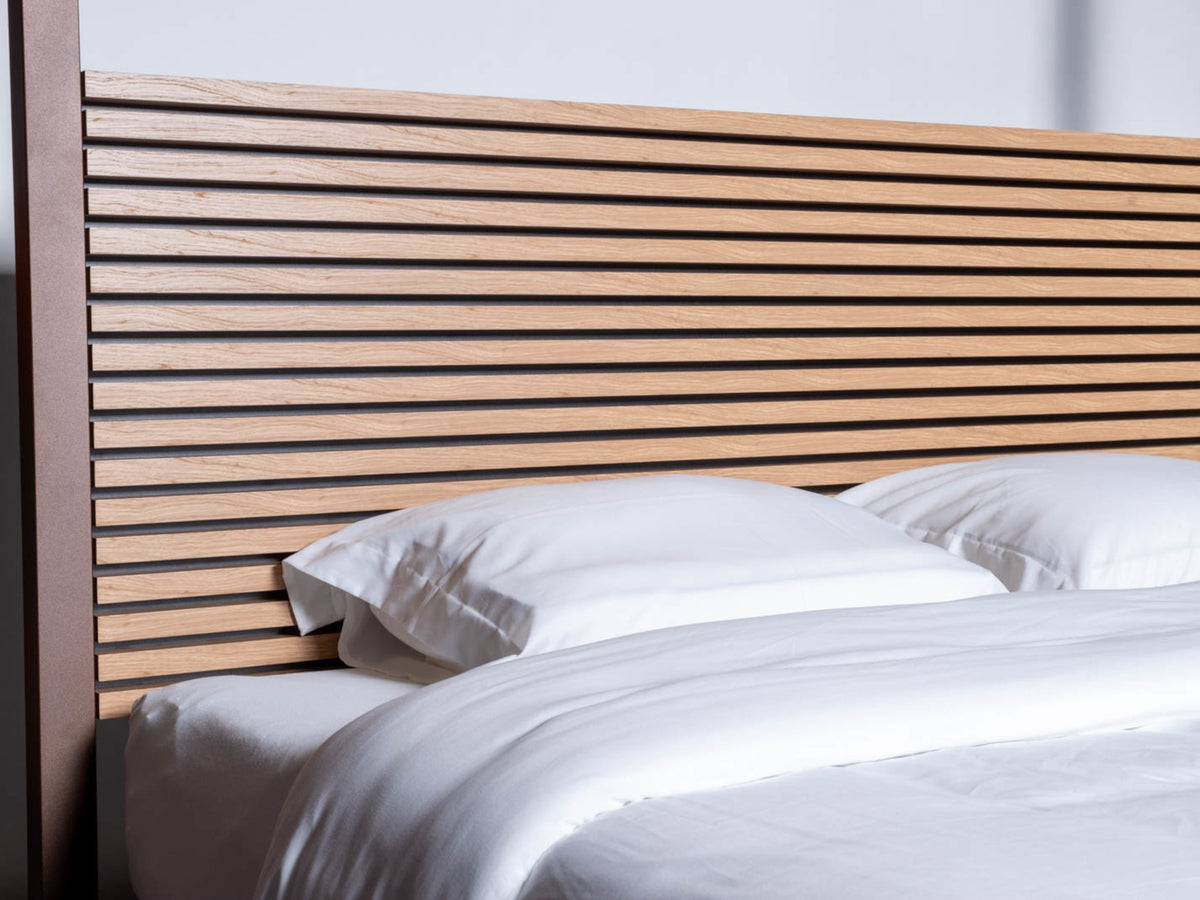 Wooden slats of The Loft canopy bed with headboard, seen close up behind white pillows