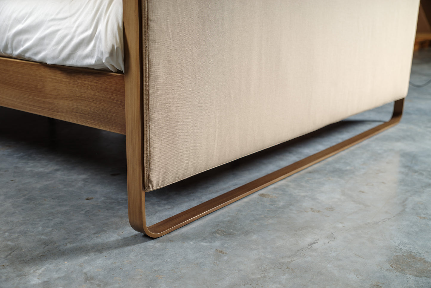 Close-up van metalen frame en beige textiel van bed Milano met strakke lijnen