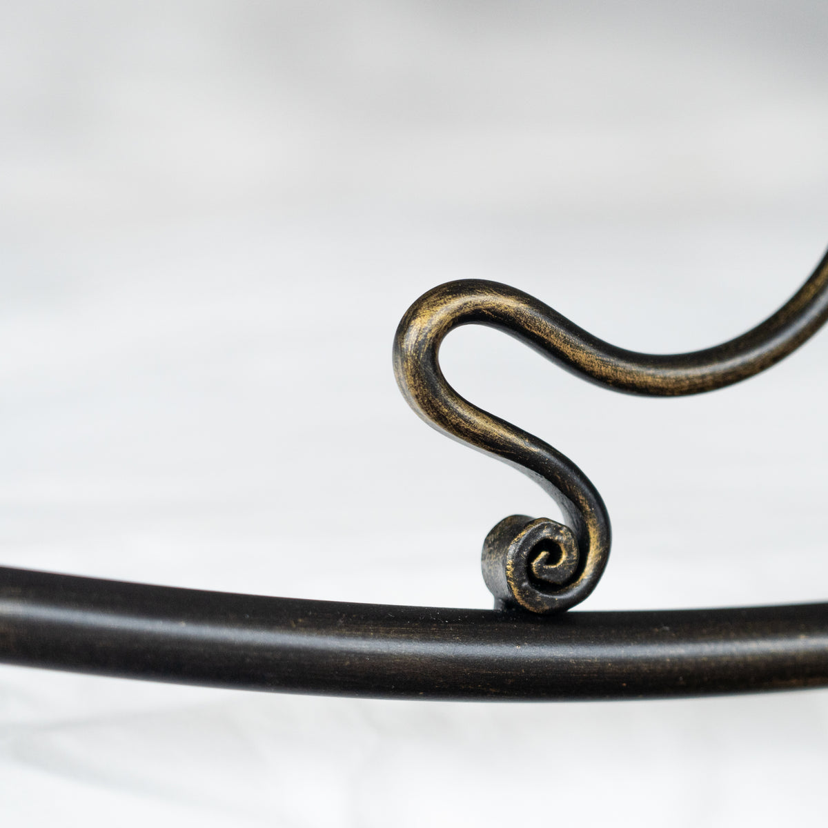 Detail eines kleinen Spiralschnörkels am oberen Rand des Betts Navarra, schwarz mit bronzenem Glanz