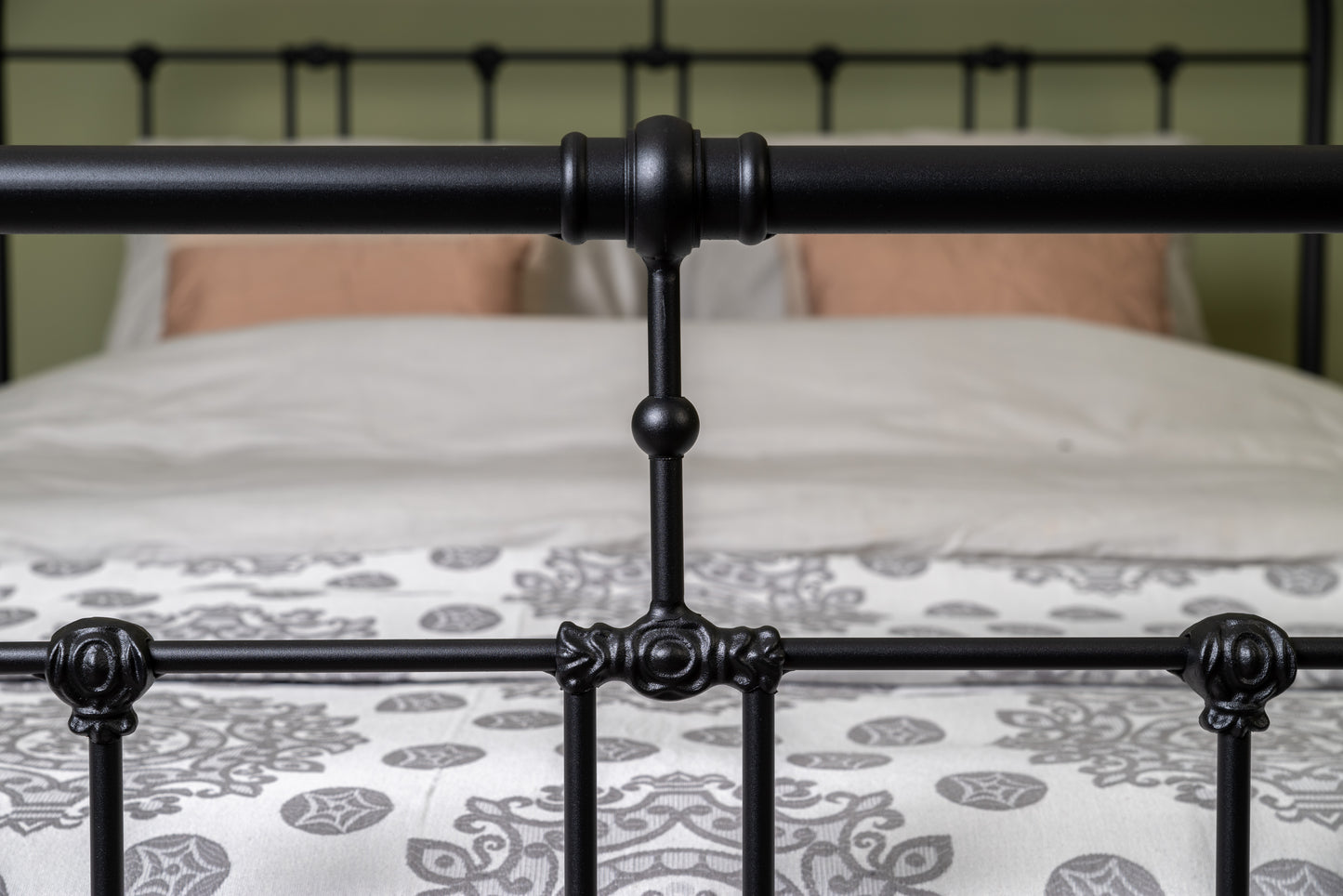 Detail centrale verbinding van zwart metalen bed Veurne met sierlijke ornamenten