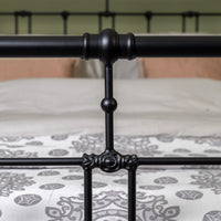 Detail centrale verbinding van zwart metalen bed Veurne met sierlijke ornamenten