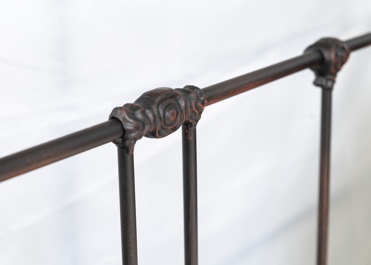 Close-up of the cast decorative joint on the top rail of the Veurne metal single bed with red-brown patina