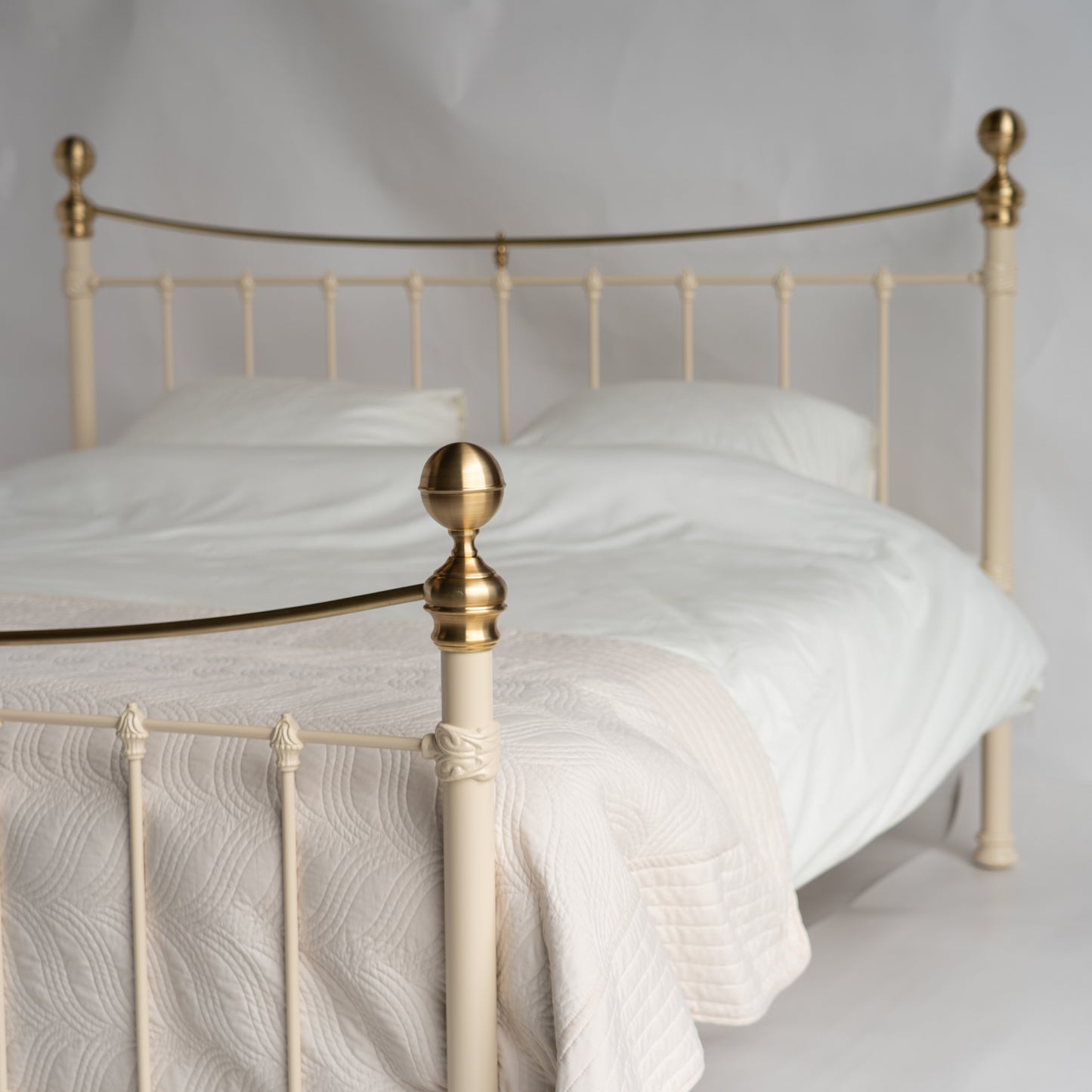 Detailshot zijaanzicht metalen bed Wellington met crèmewitte afwerking met gouden details