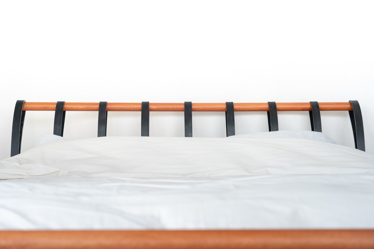 Full head end of the Cudillero metal bed with black strips and a warm wooden tube