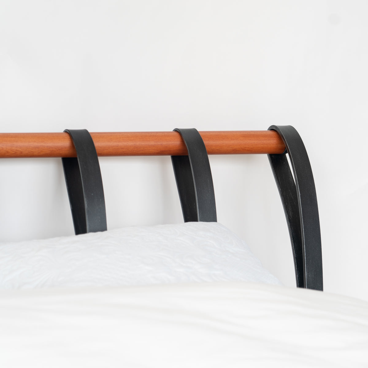 Detail of the head end of the Cudillero metal bed with black spindles and its distinctive wooden tube