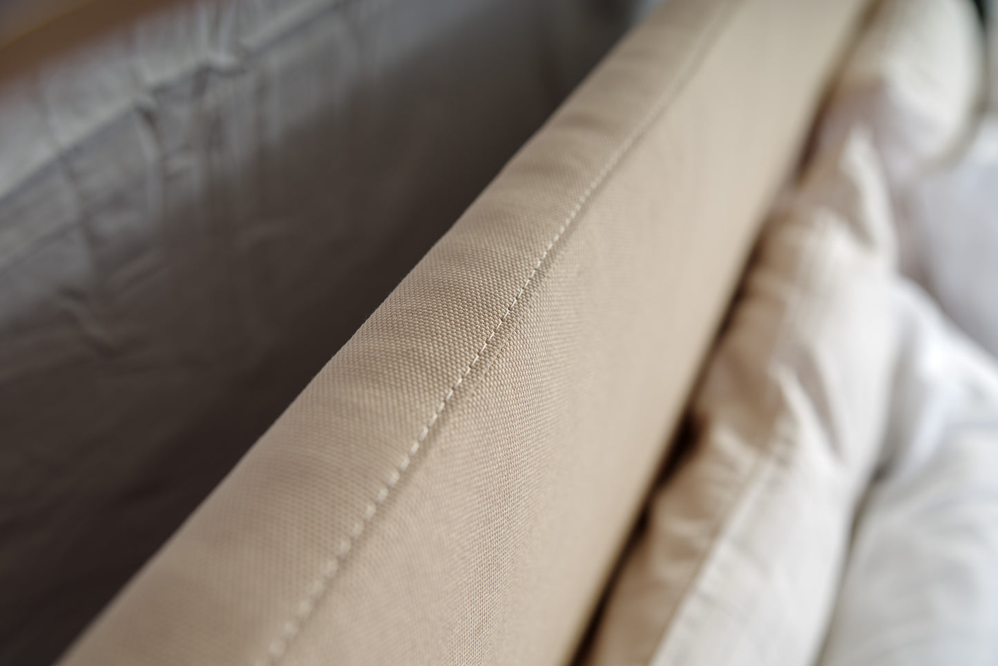 Detail precision stitching on beige upholstery of bed Milano